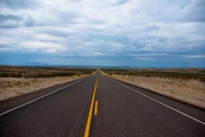 Long empty two-lane highway stretching to the horizon under a wide Texas sky
