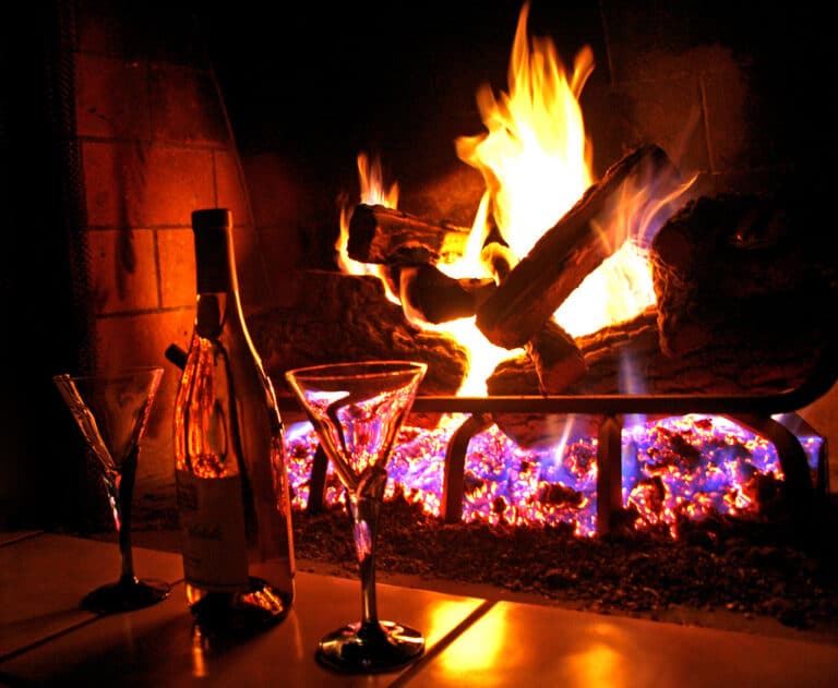 Open fire in a fireplace with a bottle of wine and glasses, a cozy evening at a vacation home
