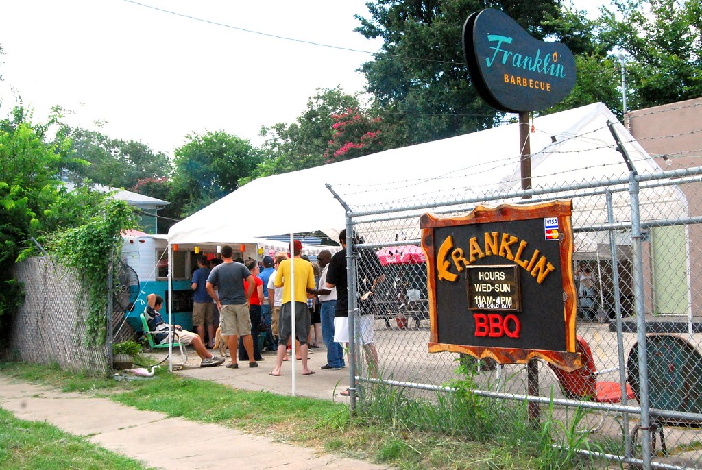 The Franklin Barbecue sign in East Austin with the queue of customers waiting outside under the tent